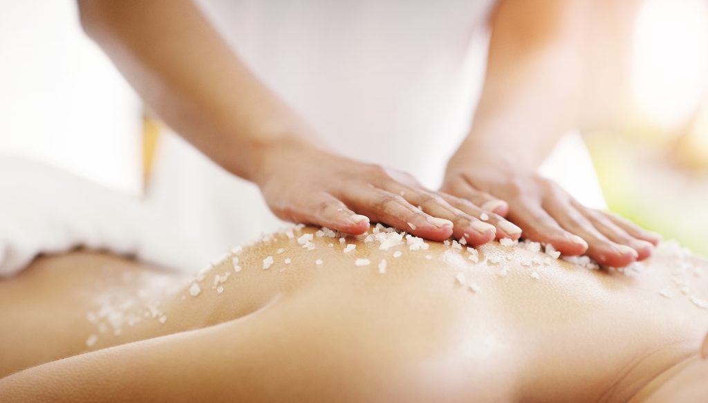 Spa, salt and woman hands massage client for skin care, self love and luxury stress relief for the body to relax. Scrubbing, beauty and person in a dermatology salon to exfoliate for wellness